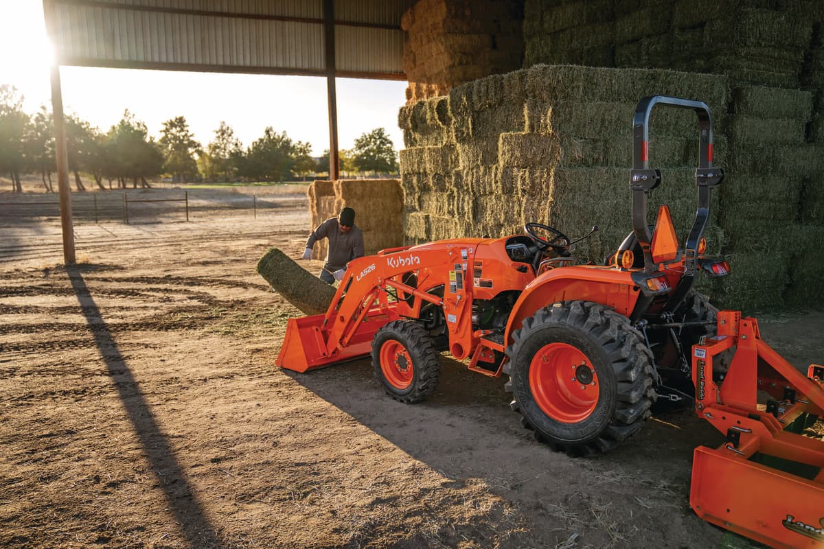 man putting square bales into front loader L3902
